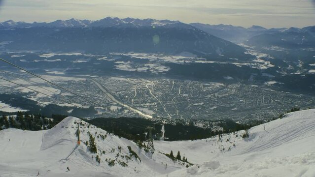 view of Innsbruck from Nordkette ski resort, with chairlift and skiers (wider)