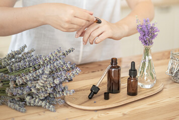 Essential oils of lavender in a glass dark bottle. The girl cares for the skin and hair....