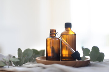 Essential oils in glass dark bottle. Skin and body care treatment concept. Eucalyptus branch.