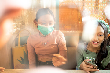 Two Asian teen girls hangout together with only one of them wearing face mask