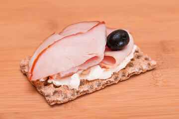 Whole Grain Crispbread with Ham, Cream Cheese and Olives on Bamboo Cutting Board. Easy Breakfast....
