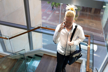 African american albino mid adult businessman with bag talking on phone while climbing steps