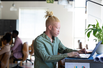 African american mid adult albino businessman using laptop while working at table in office