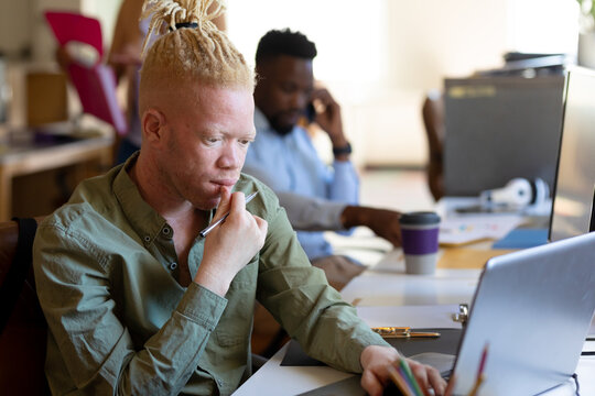 African american mid adult albino businessman working on laptop at desk in office
