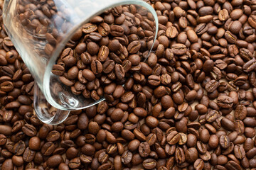 Roasted coffee beans. Place for your text and label. Coffee beans are poured from a glass cup. Advertising layout for a coffee shop and store. Top view, flat lay. Copy space. Concept.