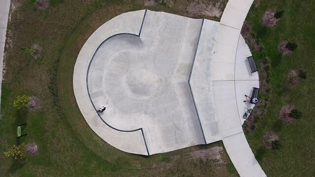 Aerial drone shot of skateboarder skating unique bowl in urban community park; 4K