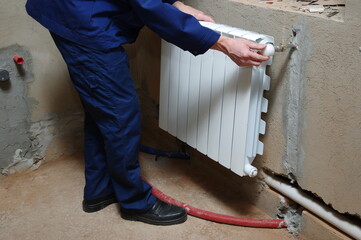 Plumber worker installing heating radiator
