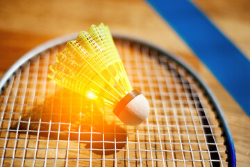 Yellow shuttlecock for badminton lies on strings of racket. Background. Close-up.