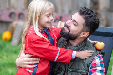 A cute blonde girl hugging her dad and both looking happy