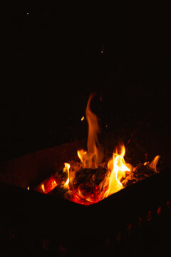 burning firewood in the brazier at night, flames of fire in the dark