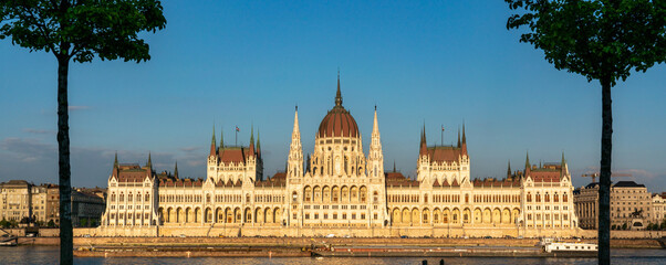 Panorama of Hungarian parliament building in Budapest framed by two trees