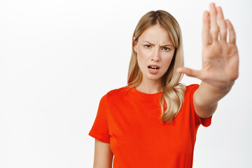 Portrait of serious young blond woman say stop, showing taboo, block refusal gesture, extending one...