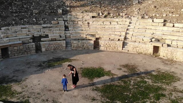 Mother With Kid Playing On The Stage Of The Ancient Greek Theater Ruins