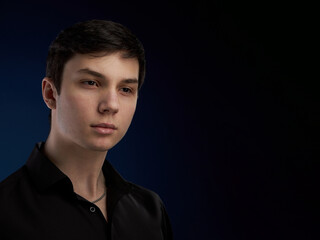 Portrait of a brunette teenager, in a black shirt on a navy blue background.