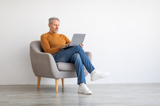 Confident mature man using laptop sitting on chair