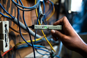 Close up shot of electrician checking current flow using continuity voltage tester on circuit board - concept of technology, repair and maintenance service.