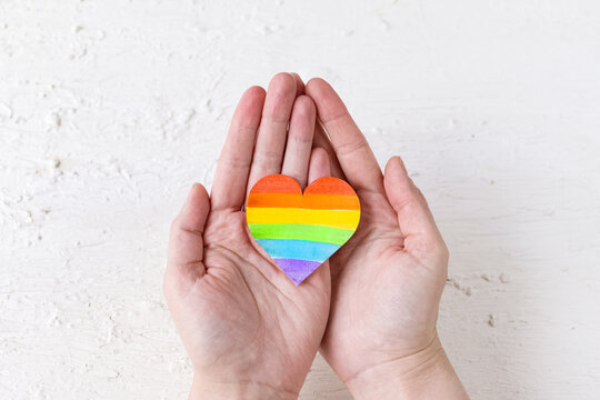 International Day Against Homophobia, Transphobia and Biphobia. May 17. Stop Homophobia. Heart with rainbow LGBT flag in the hands on white background.