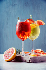 Red and white aperol spritz garnish in wine glasses with rosemary and grapefruit on luxury marble...