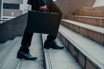 Close up legs of Businessman walks with his briefcase up stair in modern city, business growth,...