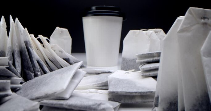 Tea bag in a white cup of tea.Super close-up set of tea bags on a white table on a black background and a white paper tea cup.