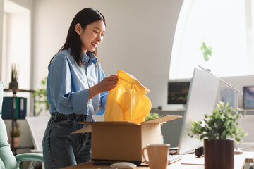 Happy Asian woman unpacking parcel after online shopping