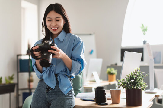 Portrait Of Asian Woman Holding Photo Camera Looking At Pictures