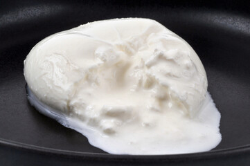 Burrata di bufala crèmeuse en gros plan dans une assiette noire
