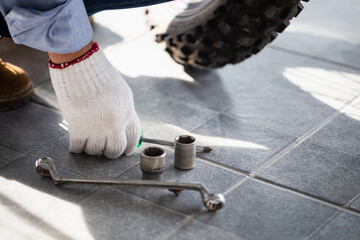 Close-up of Young man hand fixing motorcycle, Man repairing motorcycle in a repair shop, Mechanic holding screwdriver