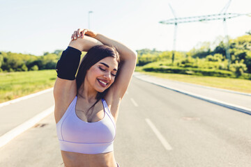 Portrait of a sporty young woman stretching her arms while exercising outdoors. Shot of a fit young woman stretching before a run outdoors. Healthy lifestyle.