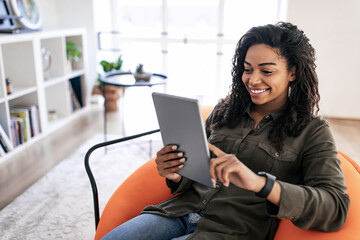 Portrait of smiling black woman using digital tablet at home - Powered by Adobe