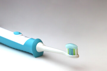 Electric toothbrush with bristle paste, white background. Dental care