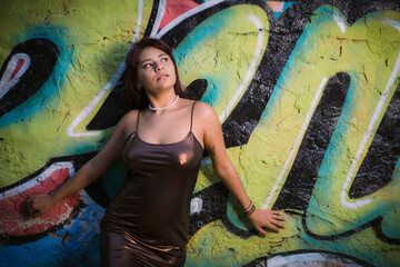 Sensual Latina posting against a wall with graffiti