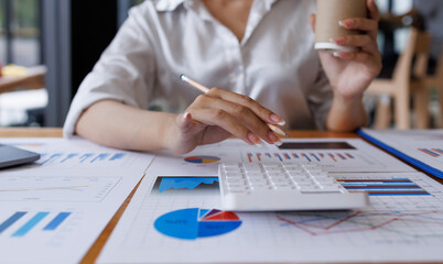 Businesswoman analyzing investment charts with calculator laptop. Accounting and technology in the office. Asian Business using laptop accountant Documents data partner deal in the workplace