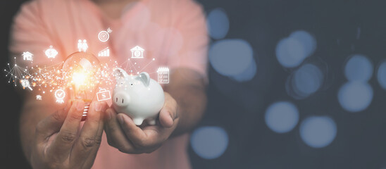 A man holding light bulb and white piggy bank with business, and financial icons on hands....