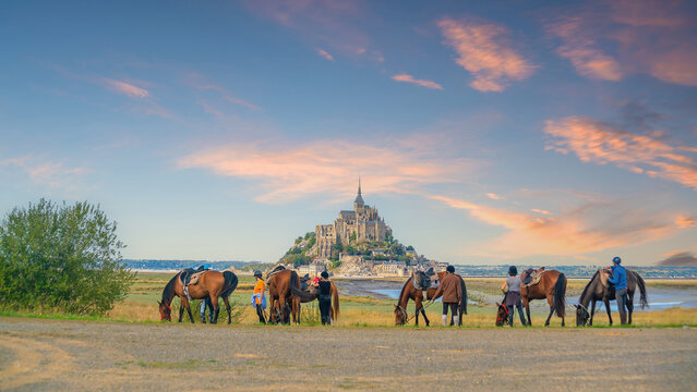 Horses and tourists with famous Le Mont Saint-Michel in Normandy, northern France