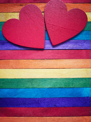 Wooden red hearts with multicoloured background. Known for LGBT symbol or abstract concept. Stock photo.