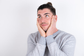 Inspired Young handsome dark haired man wearing fitted T-shirt over white wall looking at copyspace having thoughts about future events