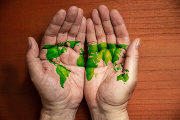 Thinking and doing ecologically. world map painted in green on the palms of a man. Top view. Conservationism, environmental association concept.