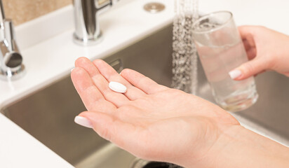 medical tablet in hand before taking it with water