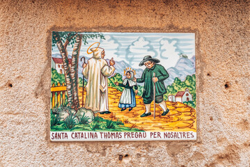 Painted tile with text. Close-up of textured wall of old building. Concept of art in structures at historic town.