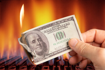 A hundred dollars are burning in your hand against the background of burning gas