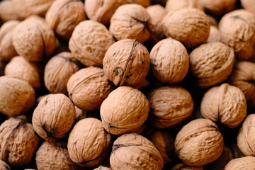 Walnuts in shell, close up, top view. Thin skinned Ukrainian varietal high-quality raw nuts. Autumn harvest, unshelled walnuts textured background.