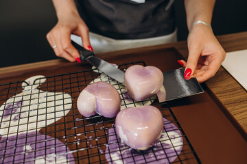 close-up of the hands of a pastry chef in a professional kitchen carefully depositing a chocolate...
