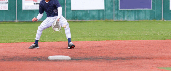 Baseball second baseman backhanding a ground ball during a game - obrazy, fototapety, plakaty