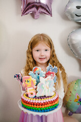 Happy birthday girl holding a cake. Decorated cake with toppers my little pony. Birthday cake for 5...