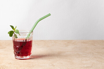 Karkade tea (hibiscus) in a glass with mint leaves and a glass tube for drinks. Horizontal orientation, copy space.