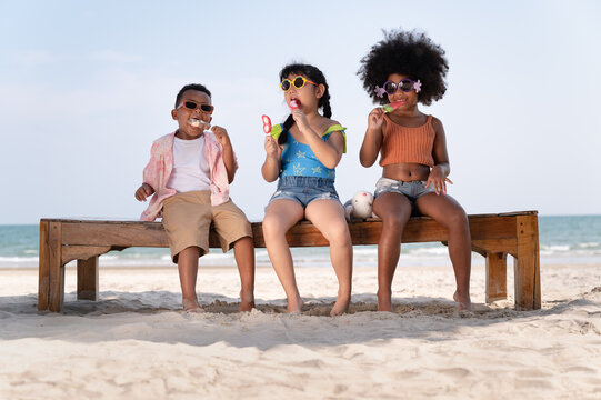 Happy fun boy and girl kids eat ice cream on the beach