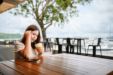 Fototapeta premium Happy Asian woman smiling brightly in a modern coffee shop drinking coffee , The concept of drinking coffee