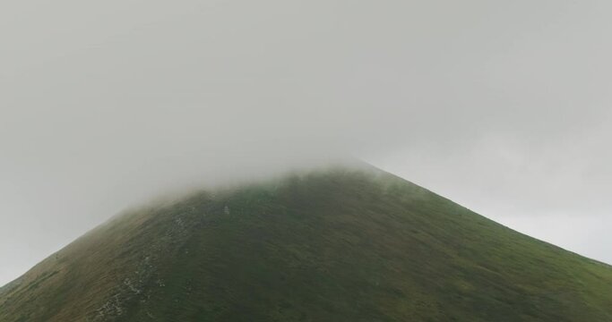 the top of the mountain covered with a gray cloud. Fog movement along Hoverla, Carpathians, Ukraine.