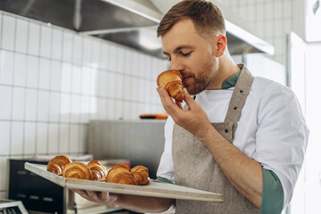 Man baker holding croissants at the bakehouse
